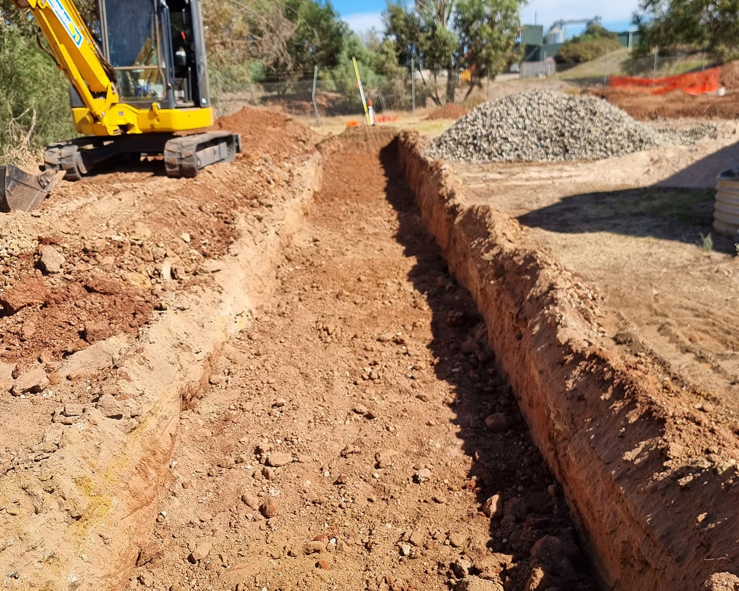 Excavator digging a trench on site for a septic and stormwater installation, an Allspec Plumbing job